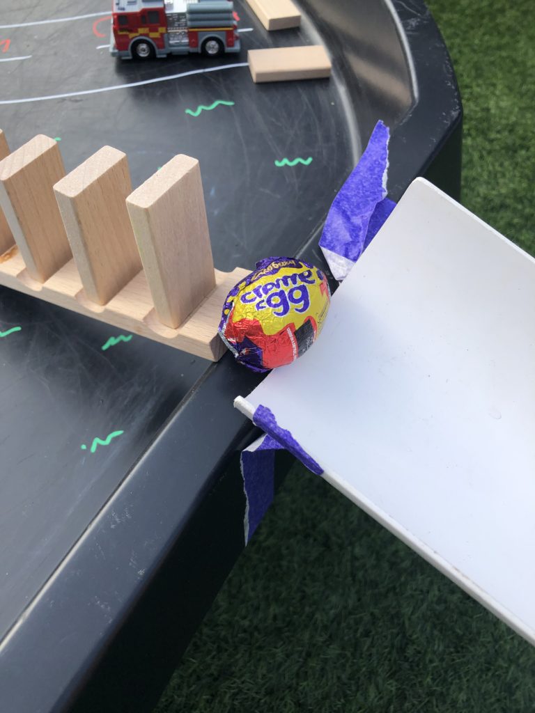 chain reaction involving a chocolate egg using dominoes and a half pipe