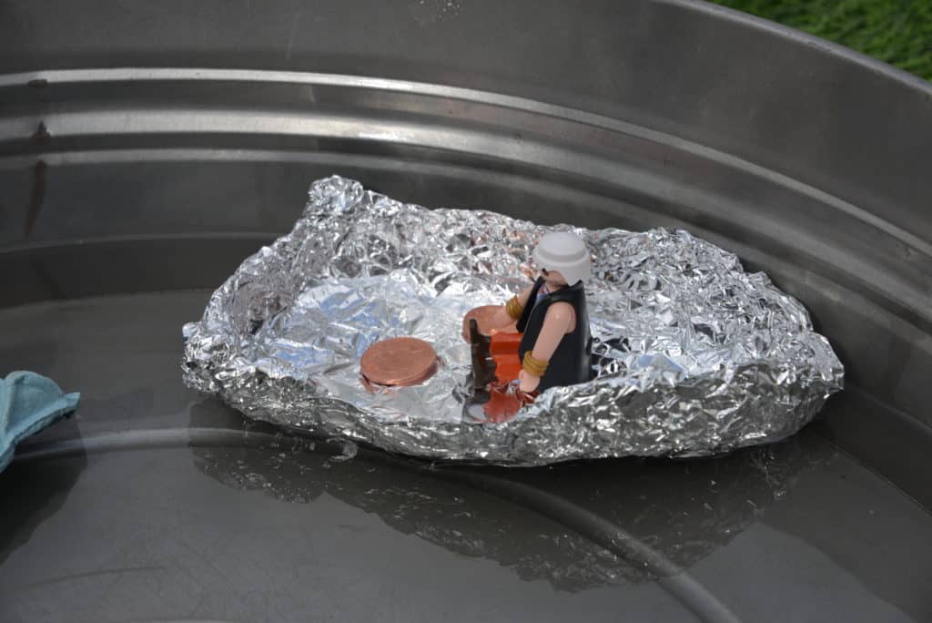 tinfoil boat with a toy figure and coins inside