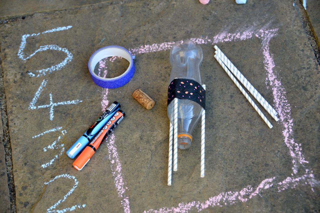 plastic bottle, straws, chalk pens, tape and a cork for making a baking soda rocket