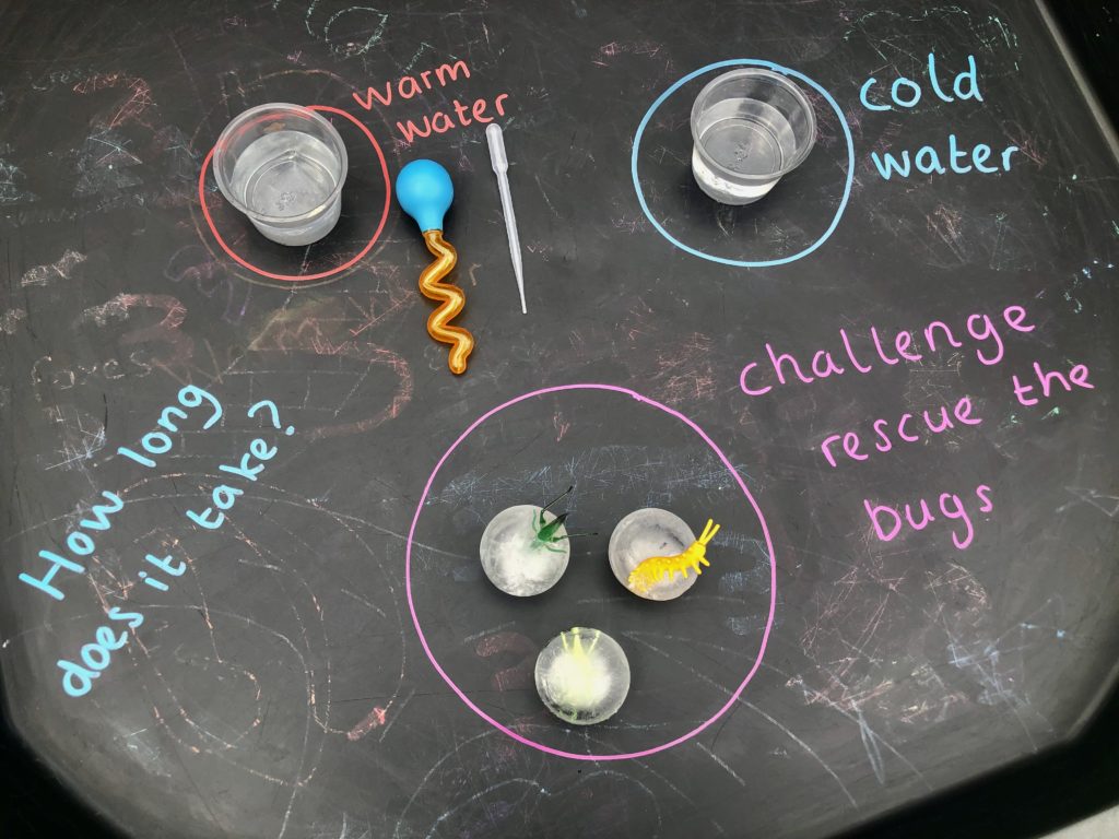 Ice cubes, pipettes and bowls full of warm and cool water on a tuff tray for a melting ice experiment - fun science for kids