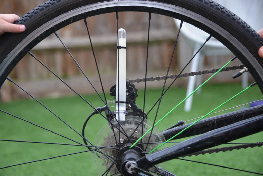 Test tube filled with oil and water tied to an upside down bike with cable ties.