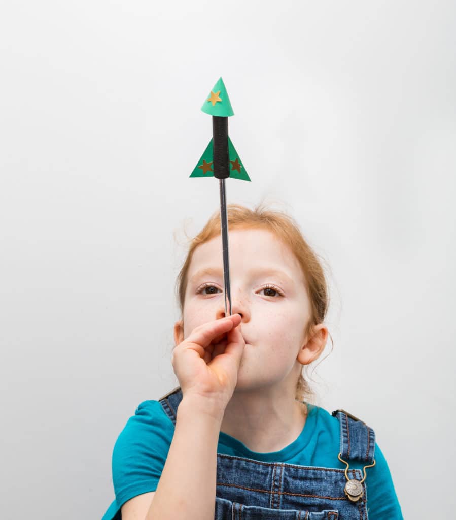 Child pointing a straw rocket into the air.