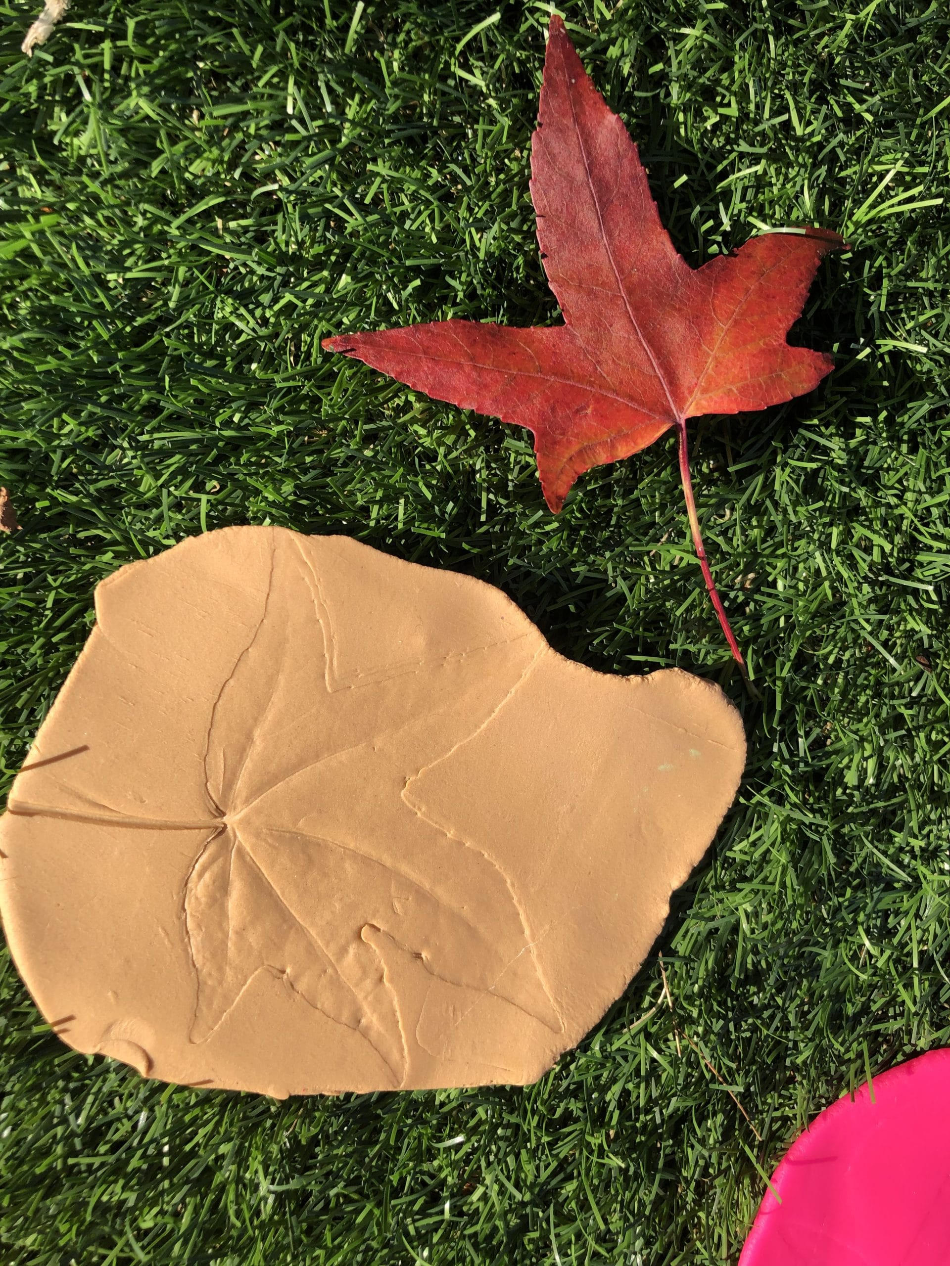 Orange play dough with a leaf imprint