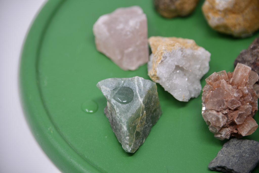 Rock samples for an impermeability test. Image shows a droplet of water remaining on the top of one rock. Part of an activity showing kids how to identify rocks