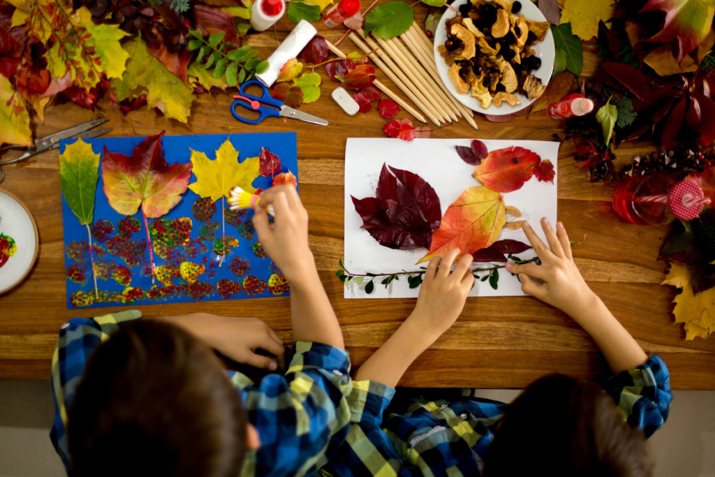 Children creating beautiful autumn collages from natural materials