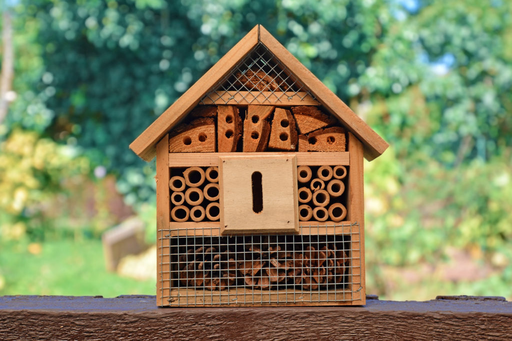 A bee hotel made from wood, tubes and other materials.