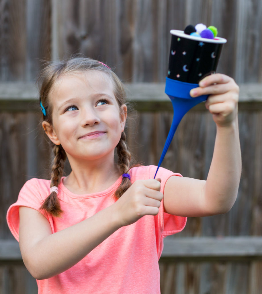 Girl holding a DIY seed dispersal machine for learning about exploding seeds