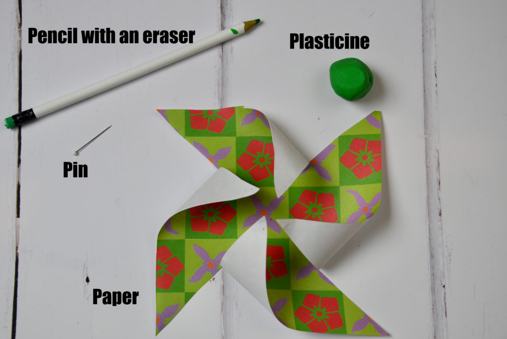 Image shows paper cut ready to make a pinwheel, a blob of plasticine, pencil with an eraser on the top and a pin