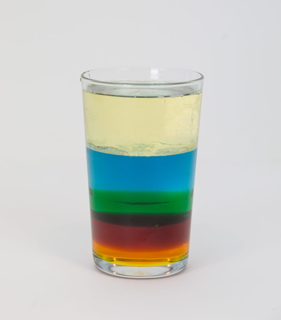 Colourful density column made with oil, blue coloured water, washing up liquid, honey and golden syrup