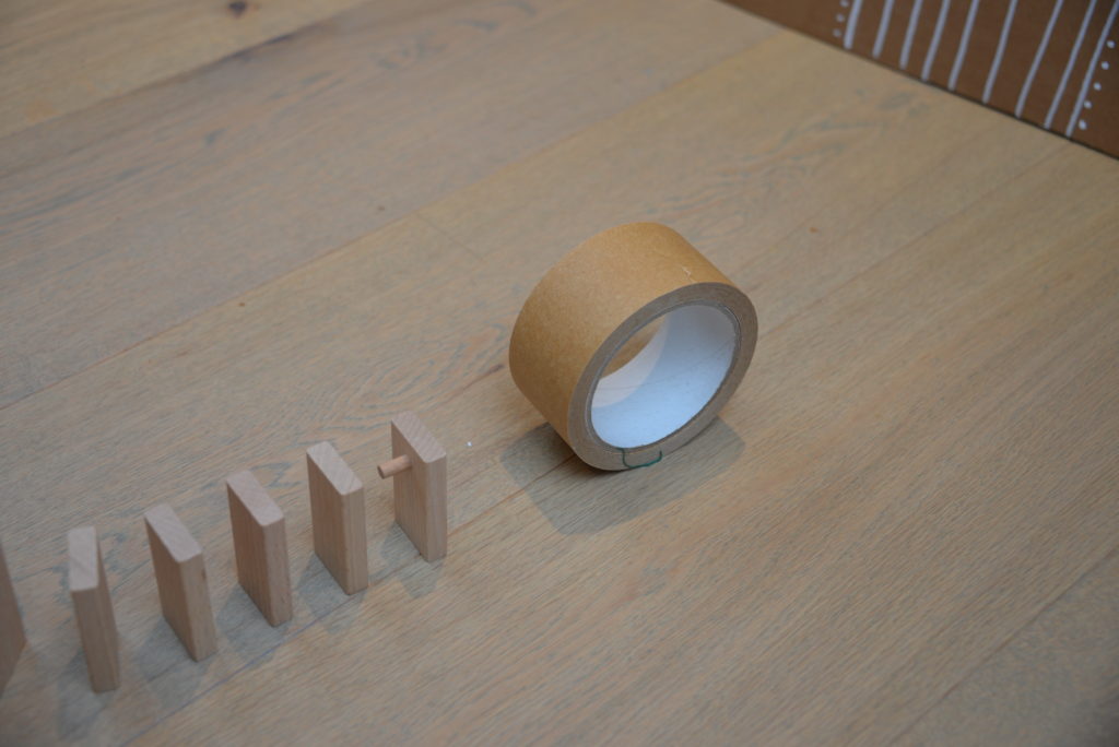 a line of dominoes and a roll of sellotape as part of a Christmas chain reaction