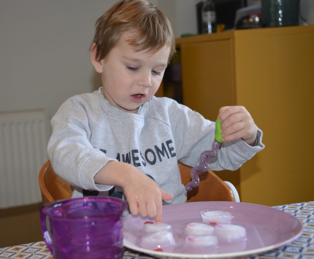 Little boy dropping warm water into ice to melt it