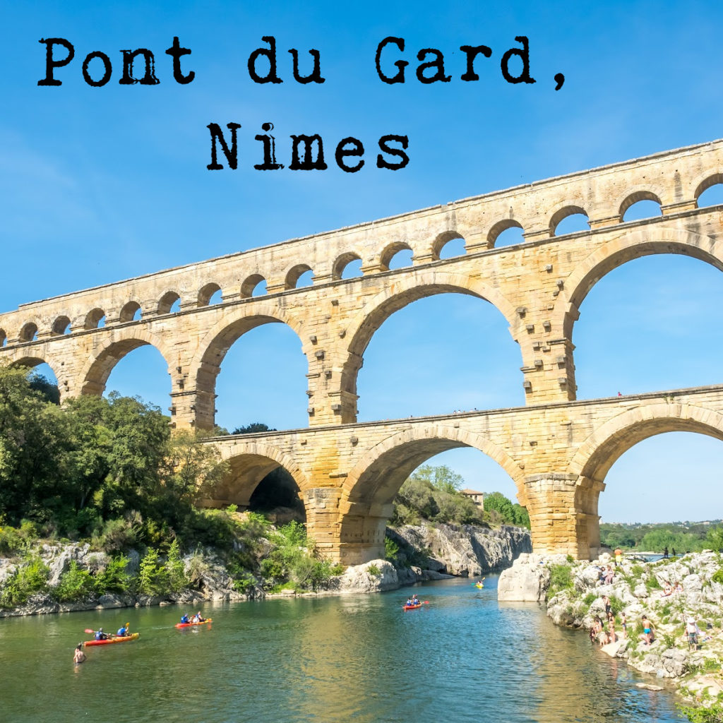 Pont du Gard in Nimes. Image shows the river underneath with 3 red  kayaks in the water