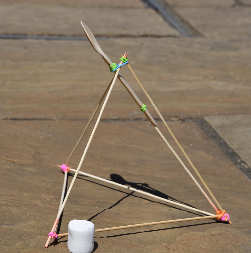 Marshmallow slingshot made with sticks and elastic bands.  A wooden spoon is used as a launch arm.