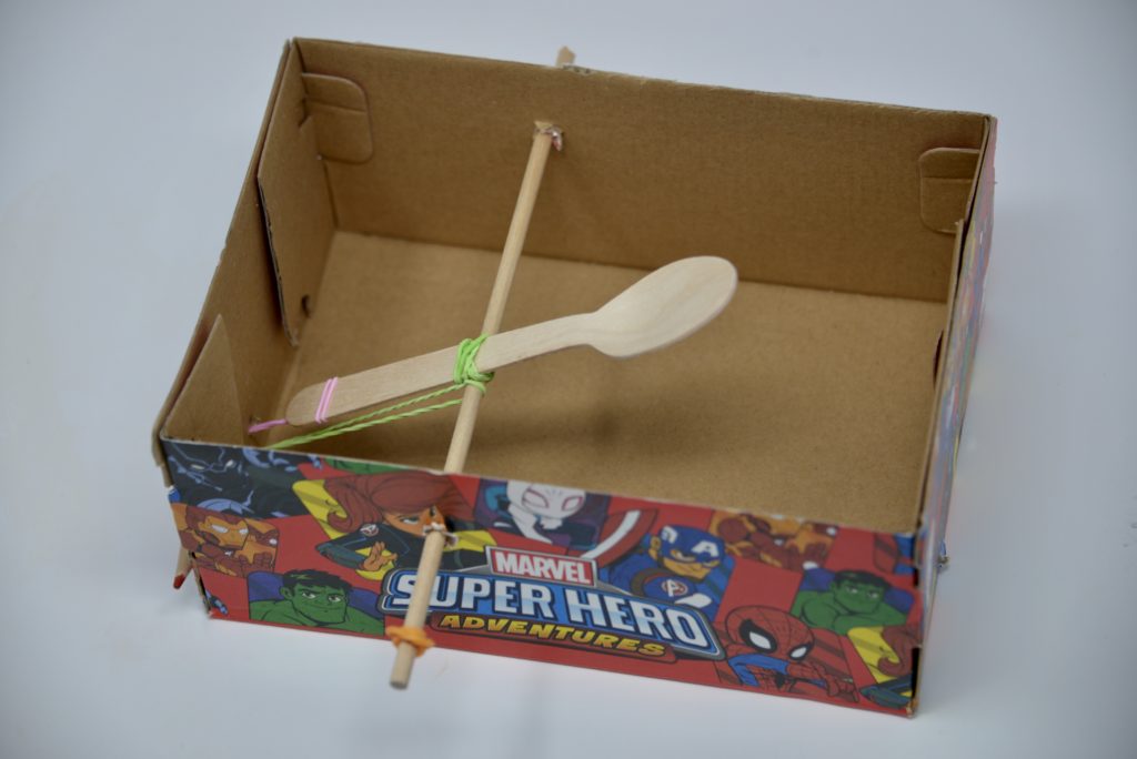 Catapult made from an empty shoebox, wooden spoon, dowel and elastic bands