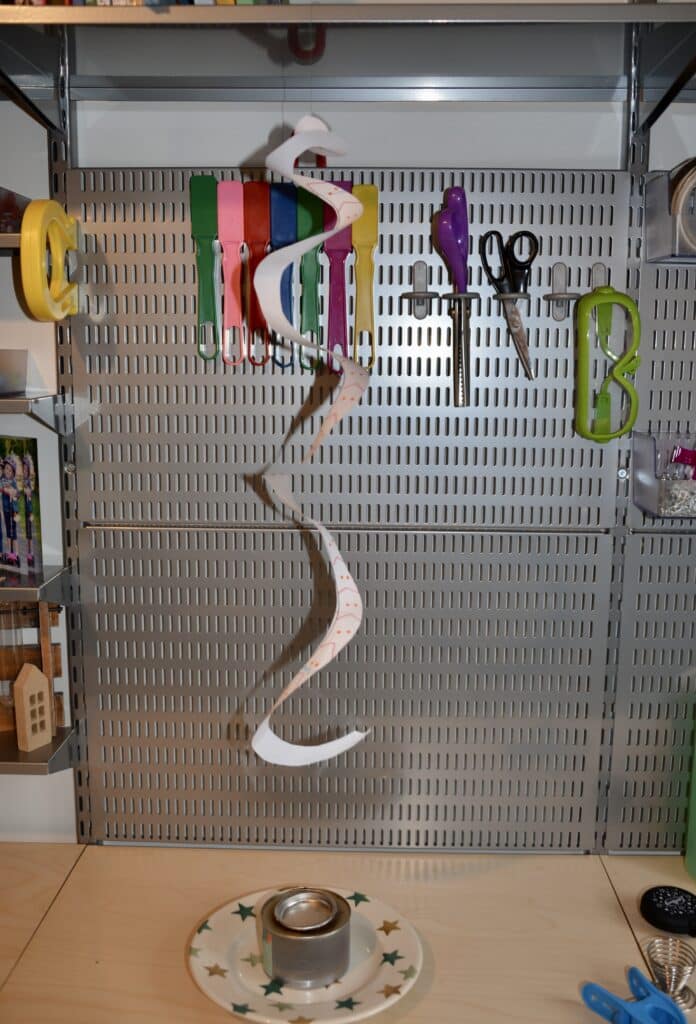 A paper spiral snake hanging from a shelf with a small candle underneath.