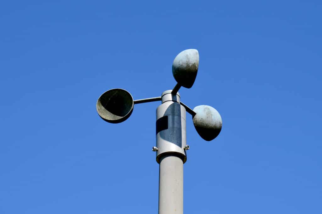 Anemometer on a tower with blue sky in the background.