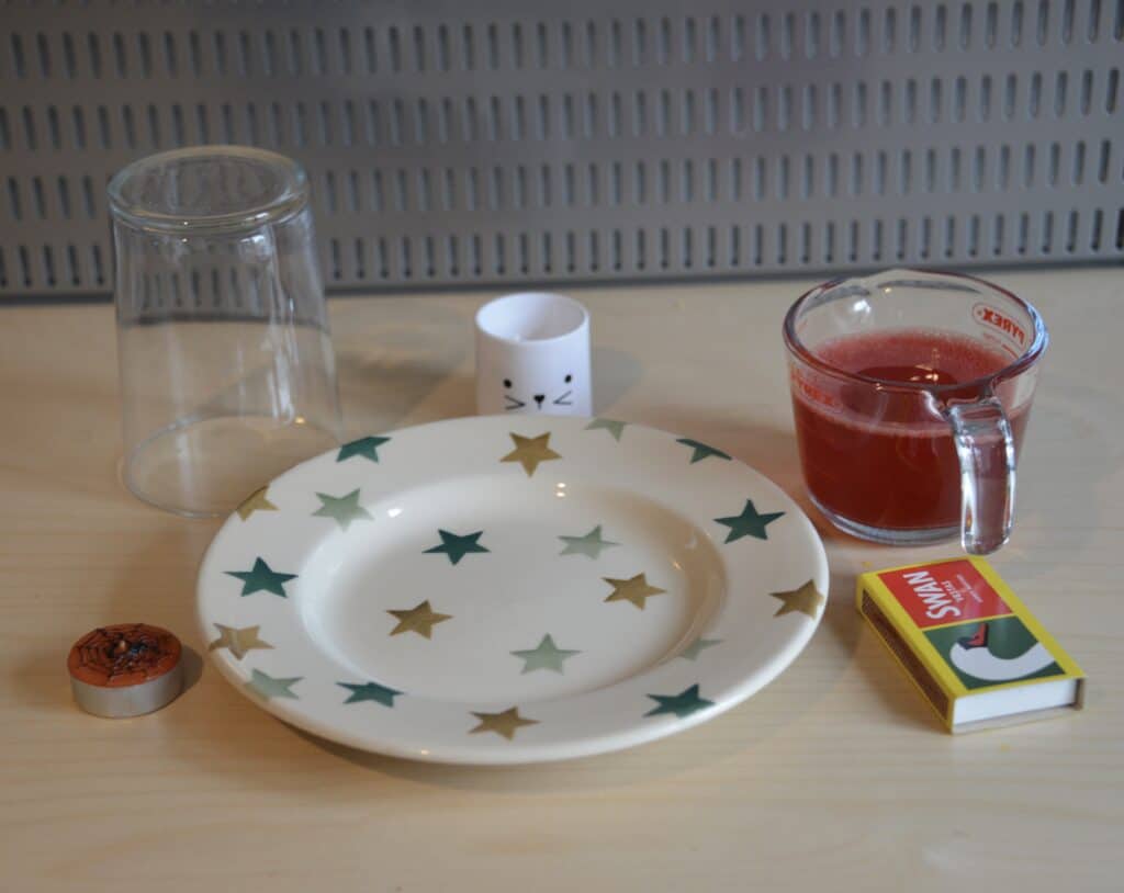 plate, pint glass, small candle, egg cup and matches for an air pressure science experiment