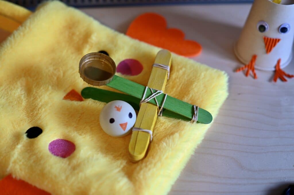 lolly stick catapult with a ping pong ball decorated like a chick
