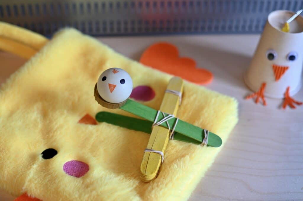 ping pong ball decorated like a chick and a lolly stick catapult