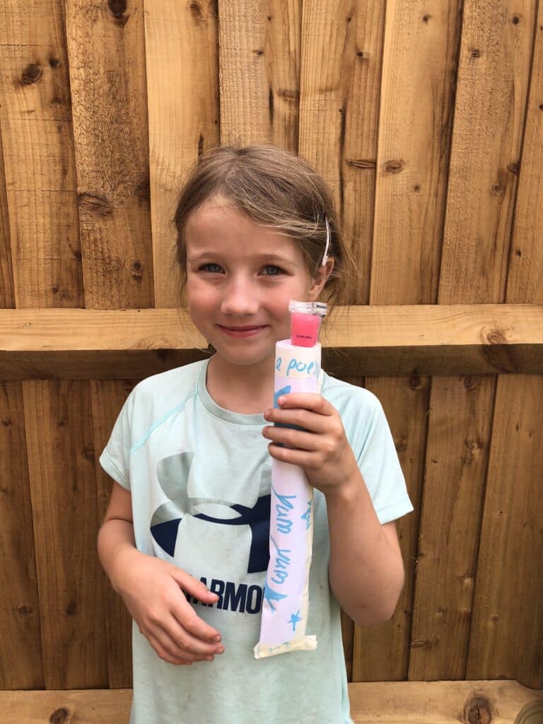Child holding an ice pop in a homemade ice pop holder for a STEM challenge