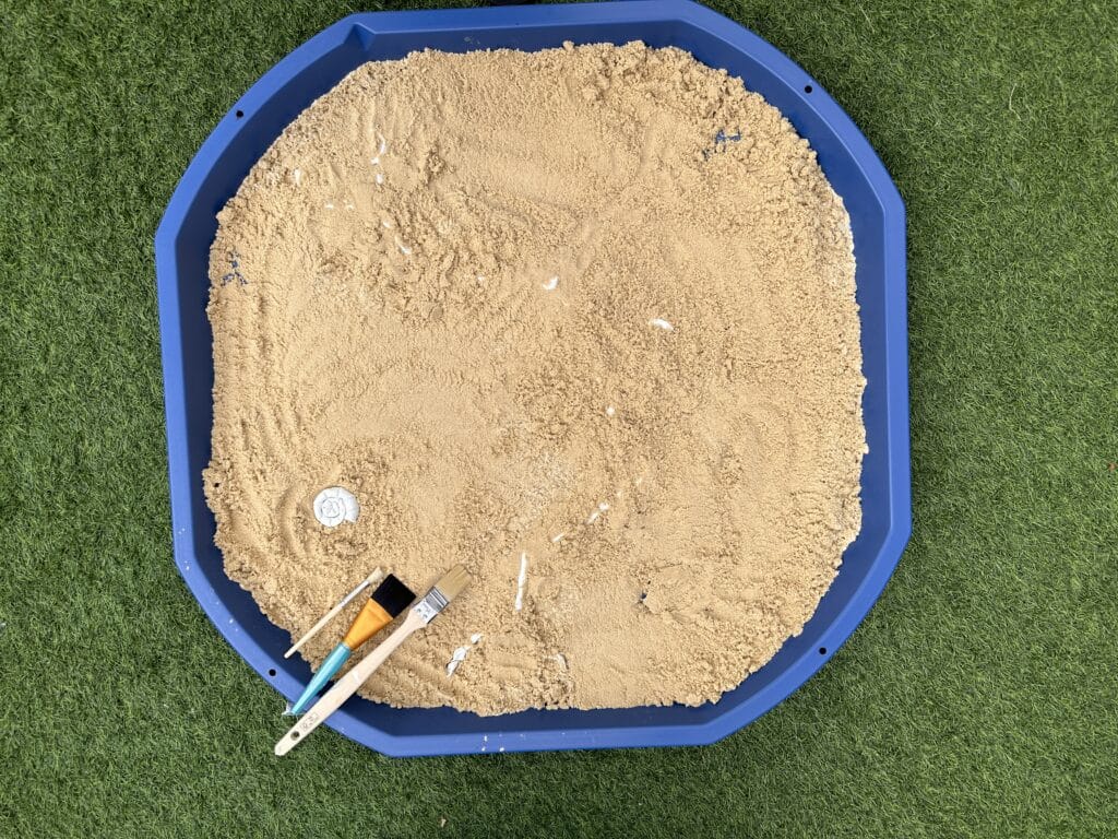 Tuff tray filled with sand with clay dinosaur bones 