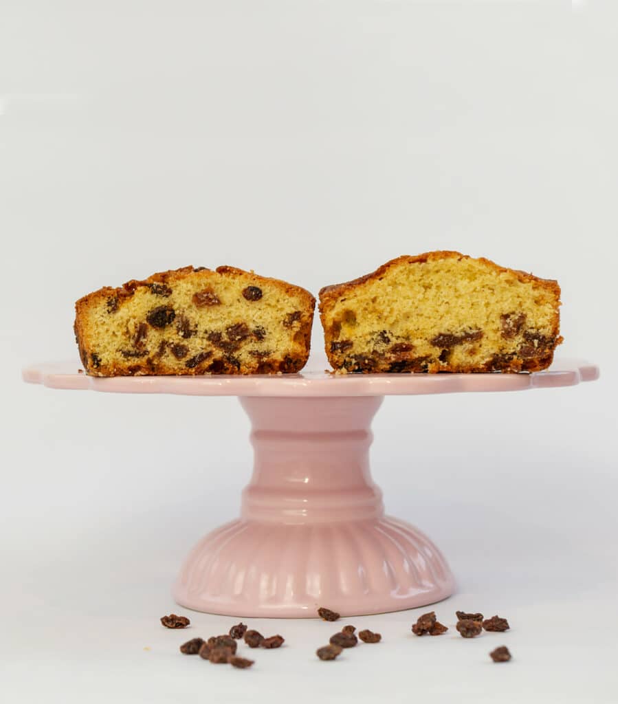 two slices of fruitcake.the raisins have sunk to the bottom of one and are spread out on the second