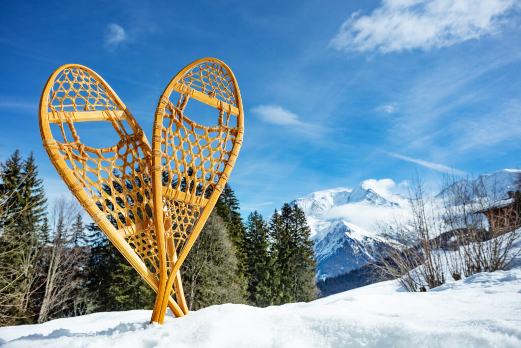 Pair of the wooden snowshoes in the snow with Alps Mont Blanc mountain peak on background
