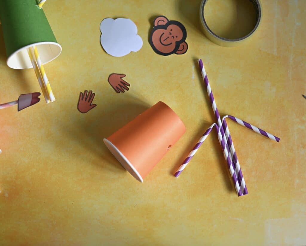 three straws taped together and a paper cup for making a puppet