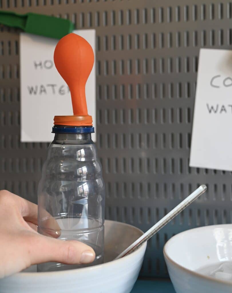 A plastic bottle with a balloon on top. The balloon is slightly inflated